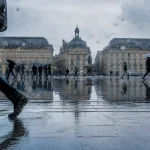 Visiter bordeaux sous la pluie, place de la Bourse : parapluies et pavés mouillés
